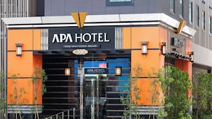 A modern hotel entrance with a prominent sign, a glass door, and a landscaped area with plants. - APA Hotel Keisei Ueno Ekimae Minami (Tokyo)