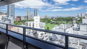 Une vue sur une ville avec de hauts immeubles, un ciel dégagé et une perspective depuis un balcon.