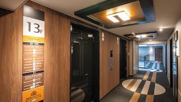 A hotel corridor with a floor guide sign, an elevator, and a patterned carpet.