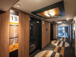 A hotel corridor with a floor guide sign, an elevator, and a patterned carpet.