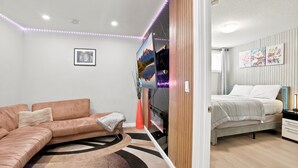 Um quarto moderno com cama, sofá, televisão e obras de arte nas paredes.