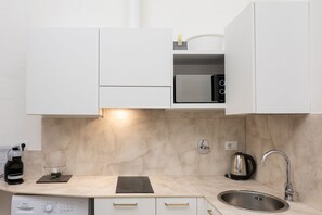 A modern kitchen with white cabinets, a built-in microwave, a kettle, and a coffee maker. - Renovated 1BR w/Balcony | WiFi | Self Check-in (Torino)