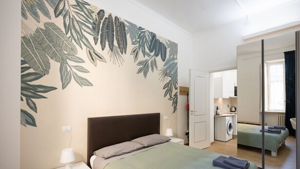 Un dormitorio con cama, mesita de noche y un espejo grande.