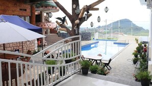 A pool area with a tree sculpture, outdoor seating, and a view of the landscape. - Azana BeSt Hotel Batu (Batu)