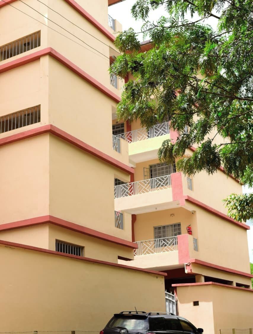 Un immeuble à plusieurs étages, doté de balcons, avec un arbre au premier plan.
