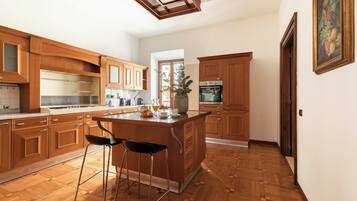 Eine Küche mit Holzschränken, einer zentralen Kochinsel mit Hockern, einem Kühlschrank und einem Bild an der Wand.