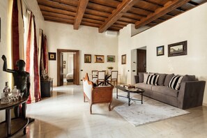 A spacious living room with a wooden ceiling, a sofa, a coffee table, and a dining area with chairs and a table. - Elegant Historic Home with Direct View of Piazza Venezia - Capitol House (Roma)