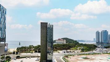 A modern building with a glass facade, surrounded by a parking lot and a body of water.