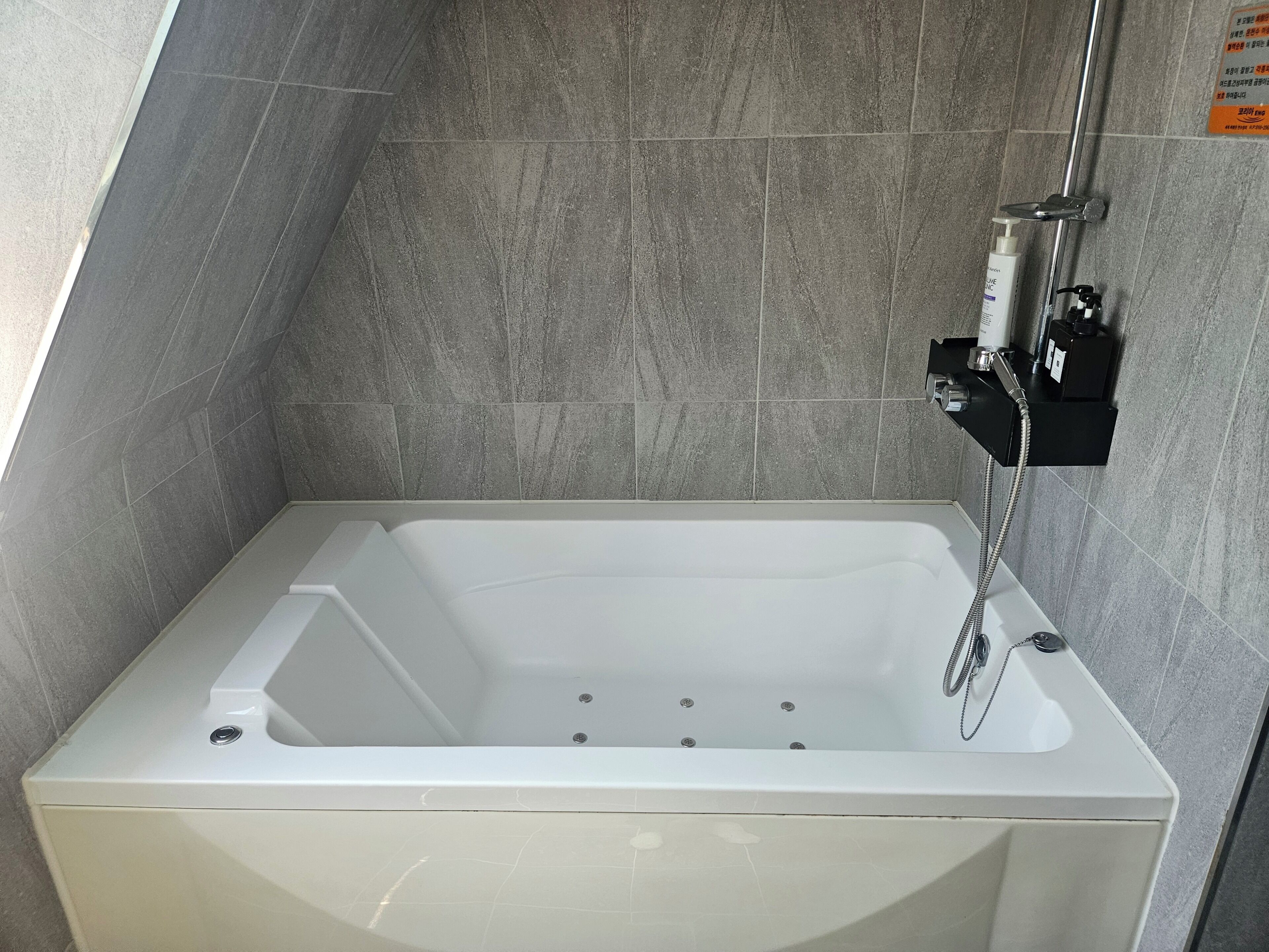 A modern bathroom with a freestanding bathtub, a handheld showerhead, and a wall-mounted control panel.