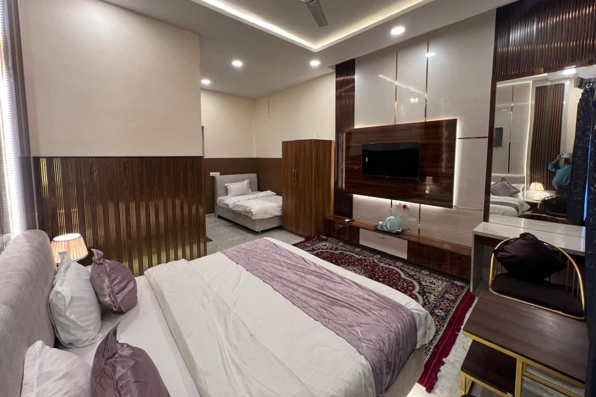 A modern hotel room with a large bed, a TV, a wardrobe, and a mirror.