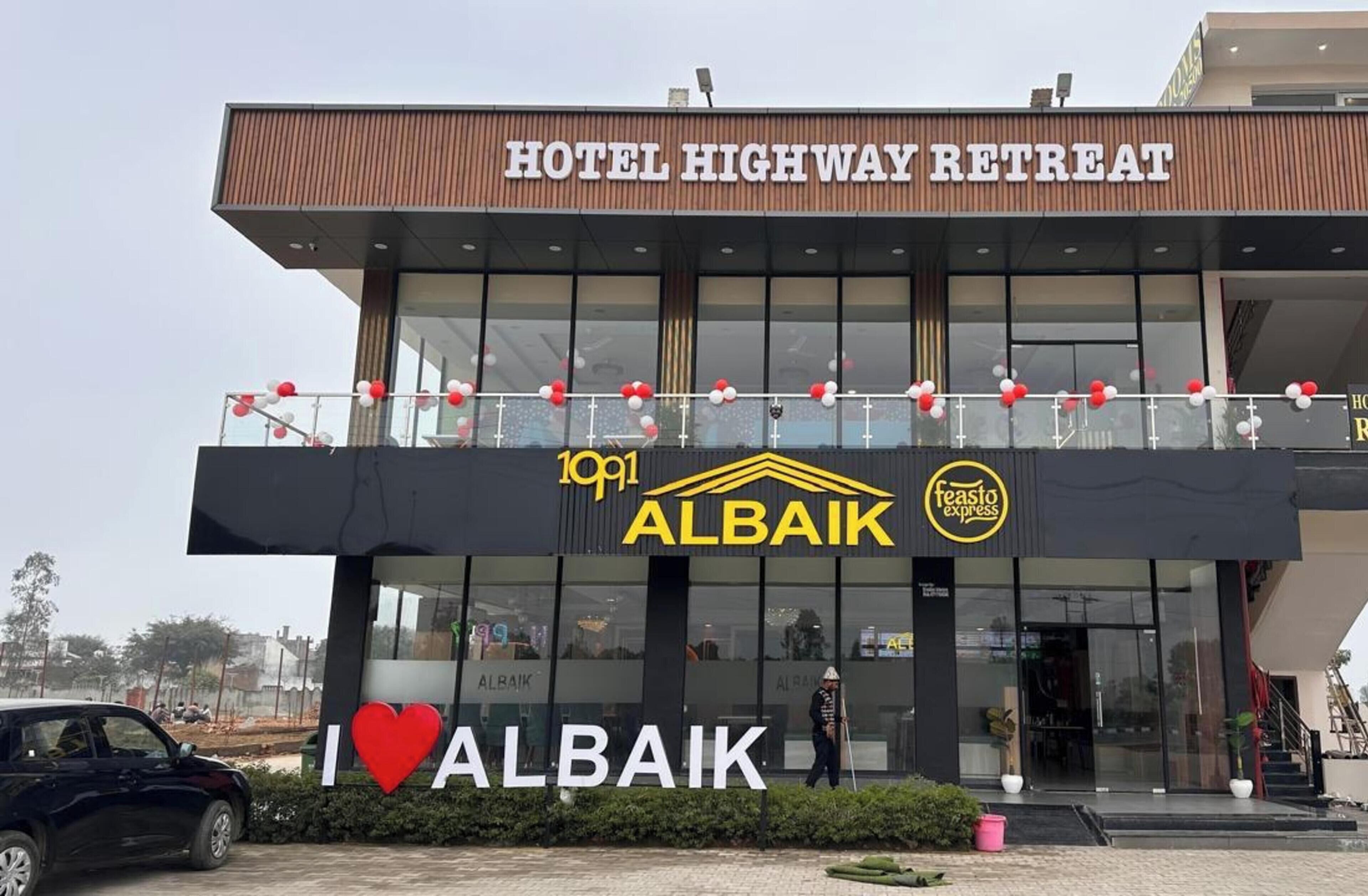 A hotel named 'Hotel Highway Retreat' with a modern facade, balconies, and a visible 'I ♥ ALBAIK' sign.