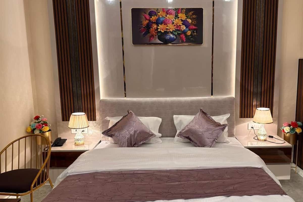 A hotel room with a large bed, two bedside tables with lamps, a chair, and a decorative wall piece.