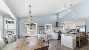 Una cocina amplia con una mesa de comedor de madera, armarios blancos y una isla grande.