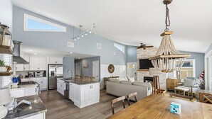 Una cocina amplia con armarios blancos, una isla central y un comedor con mesa de madera.