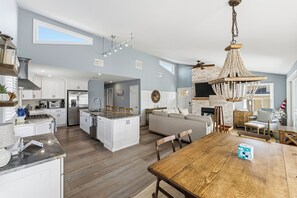 A spacious kitchen with white cabinets, a central island, and a dining area with a wooden table. - Steps to the Beach / Ocean Views, Sunset Deck, 3BR 2BA Getaway (Ocean City)