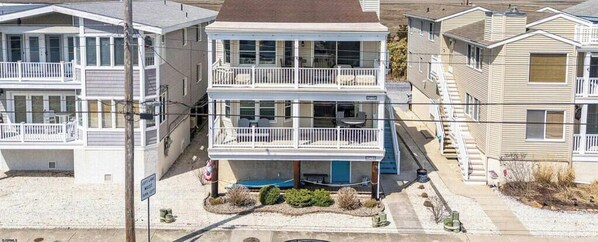 A two-story building with balconies, a swimming pool, and a beach view.