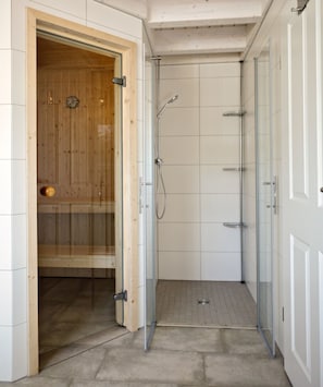 Une douche à l’italienne avec des portes en verre, un sauna en bois et des murs carrelés.