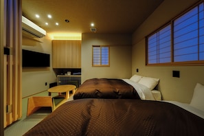 Een hotelkamer met een bed, een tafeltje, een kitchenette en een raam met uitzicht.