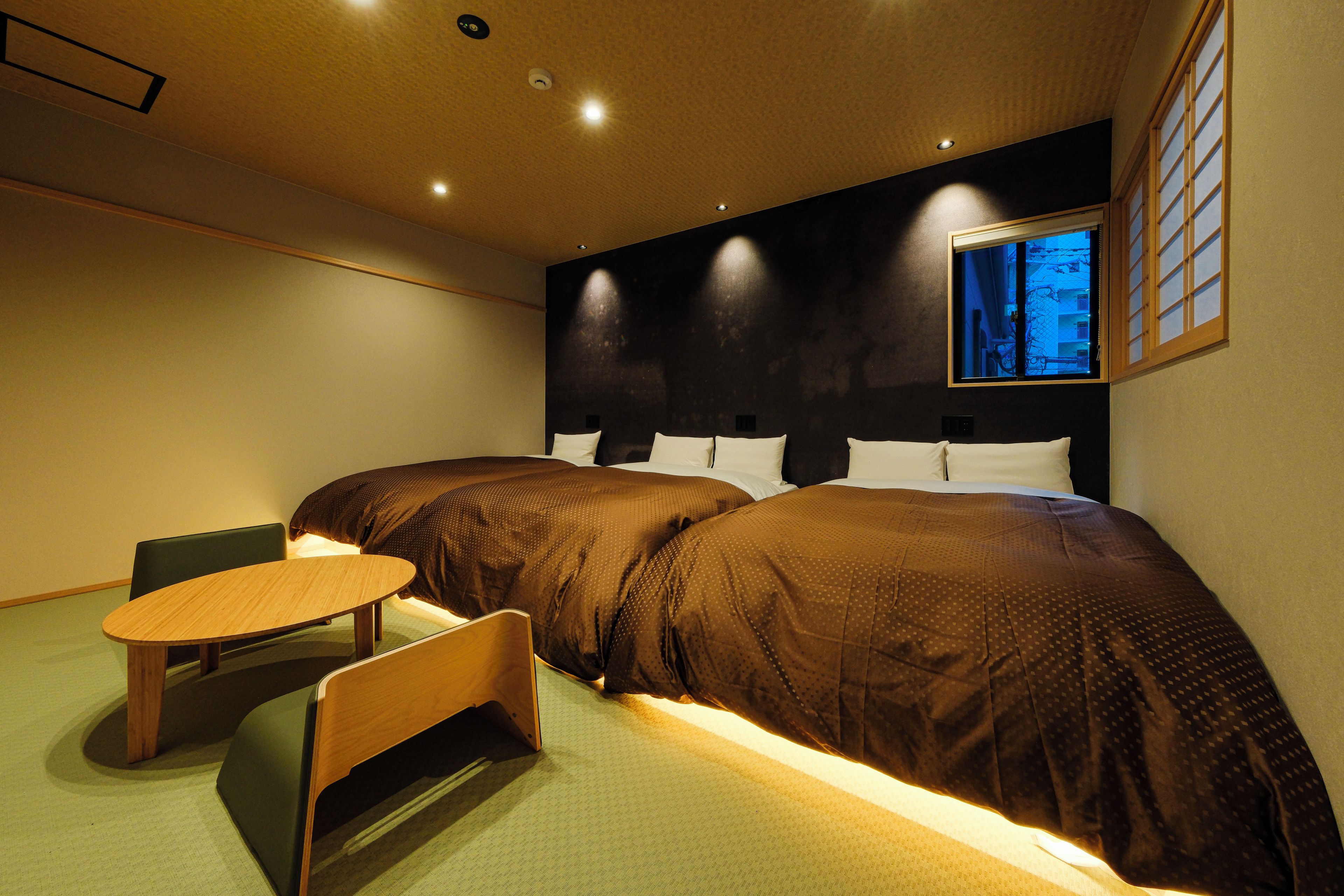 Habitación de hotel con dos camas, una mesita y una silla.