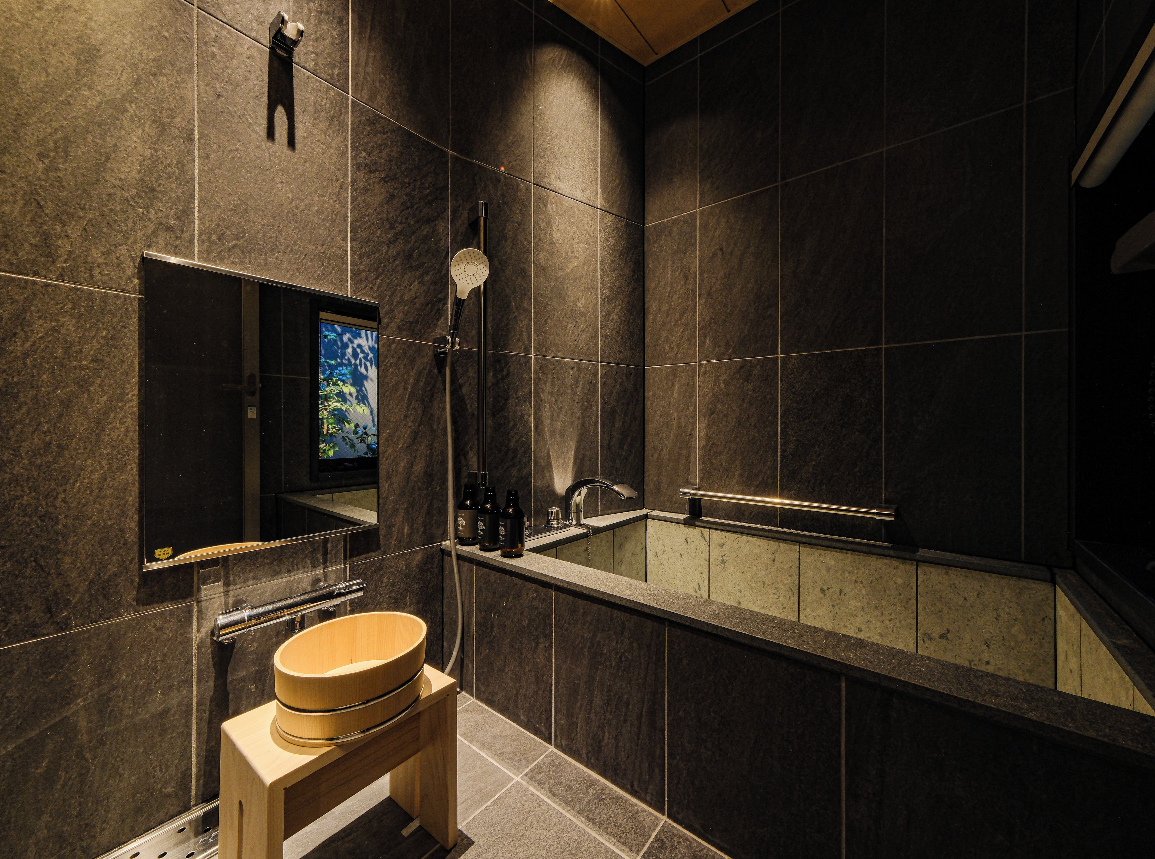 Ein modernes Badezimmer mit Toilette aus Holz, einem großen Spiegel, einer Dusche und einem Fernsehbildschirm.