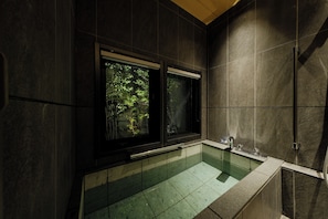 Een moderne badkamer met een douchecabine van glas, een badkuip en een raam met uitzicht op groen.
