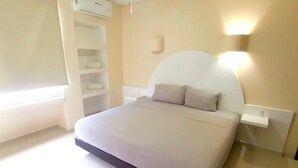 Ein Schlafzimmer mit Bett, Nachttisch, Wandleuchte und integriertem Regalelement.