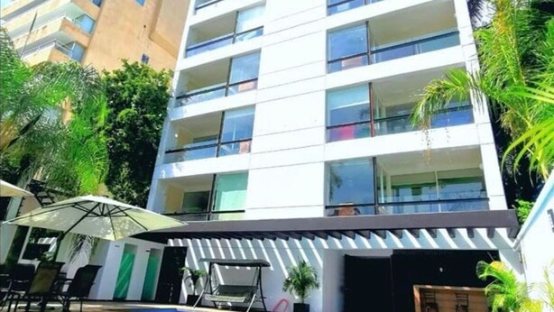 Ein mehrstöckiges Hotel mit Schwimmbad, Außenbereich und Palmen.