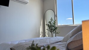 Ein Schlafzimmer mit einem Bett, einer Klimaanlage, einem Fenster und einer Pflanze.