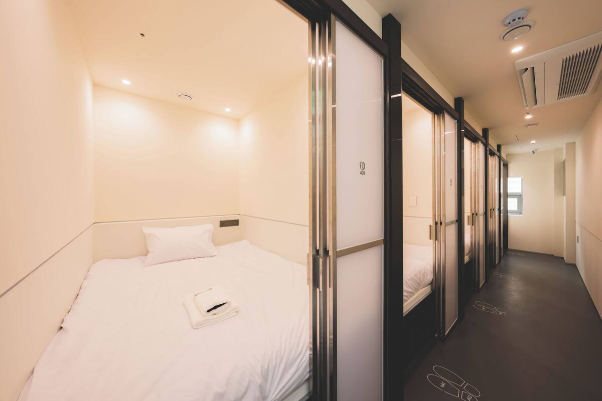 Una habitación de hotel con una cama, la puerta de un baño y un pasillo que conduce a otra habitación.