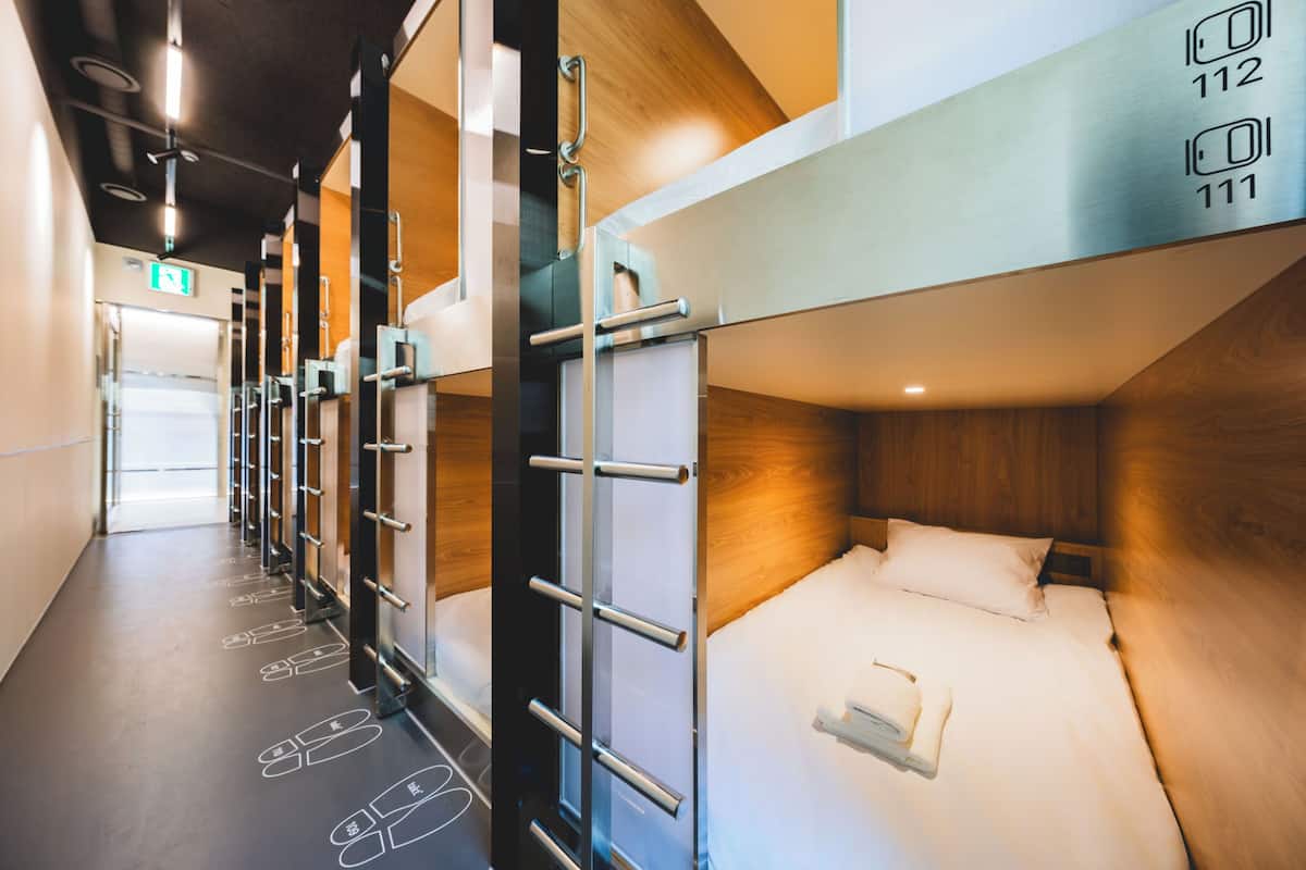 Habitación de hotel con literas, un cabecero de madera y una señal de salida visible.
