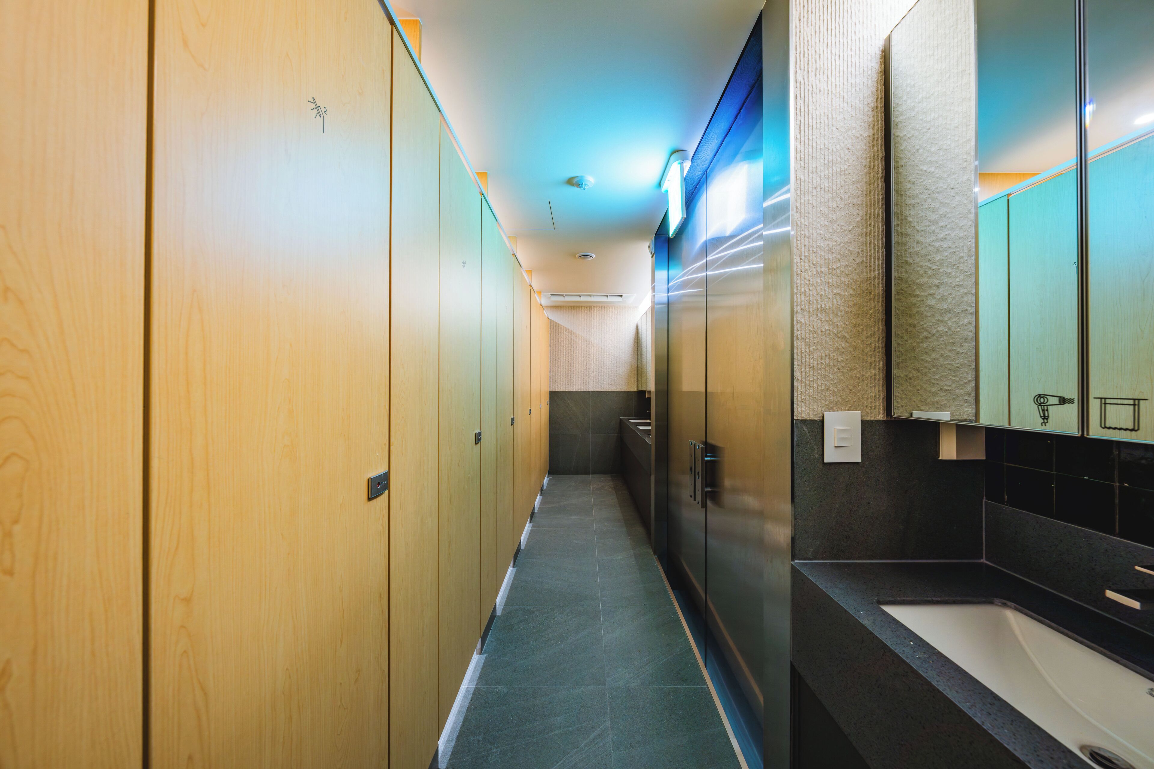 Un couloir avec des casiers en bois, un lavabo et un miroir.