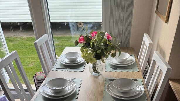 Una mesa de comedor dispuesta con platos, cubiertos y un florero.