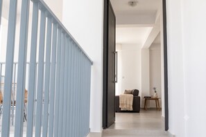 A modern interior with a staircase, a sofa, and a small table with a vase. - Sykia | Upper Floor 2-BR Apartment | (Paphos)