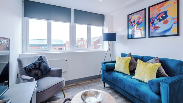 Una sala de estar moderna con un sofá, un sillón y un ventanal con persianas.