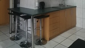 Una cocina con armarios de madera, encimera negra, microondas y fregadero.
