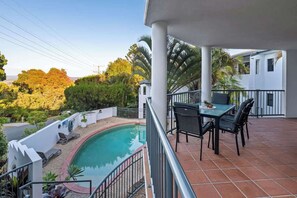 Ein Balkon mit Pool, Sitzgelegenheit im Freien und Blick auf Bäume und Gebäude.
