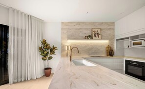 Eine moderne Küche mit Marmorarbeitsplatte, Edelstahlgeräten und einem Blumentopf.