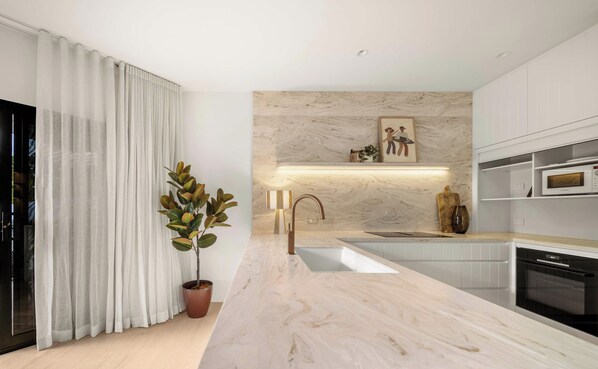 Eine moderne Küche mit Marmorarbeitsplatte, Edelstahlgeräten und einem Blumentopf.