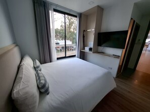 A hotel room with a large bed, a TV mounted on the wall, a window with curtains, and a view of the outside. - Double Room just 100m from Ao Nang Beach (ตำบล อ่าวนาง)