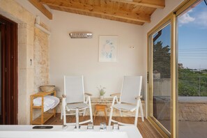Une pièce avec deux chaises blanches, une petite table, un panier et un tableau encadré accroché au mur.