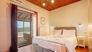 Ein Schlafzimmer mit einem Bett, Nachttischen, einem Deckenventilator und Blick durch eine Glastür.