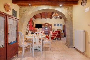 A dining area with a stone archway, a wooden ceiling, and a dining table with chairs. - Cretan Traditional Home Villa with Mountain View, Wi-Fi, and Air Conditioning (Tilisos)