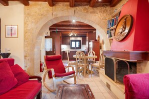 Un salon avec une cheminée, des meubles rouges et un mur en pierre.