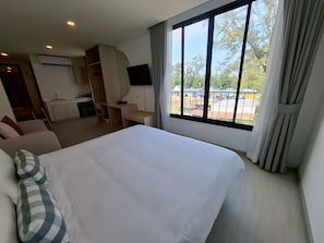 Une chambre d’hôtel équipée d’un lit, d’un bureau, d’une télévision et offrant une vue sur l’extérieur.