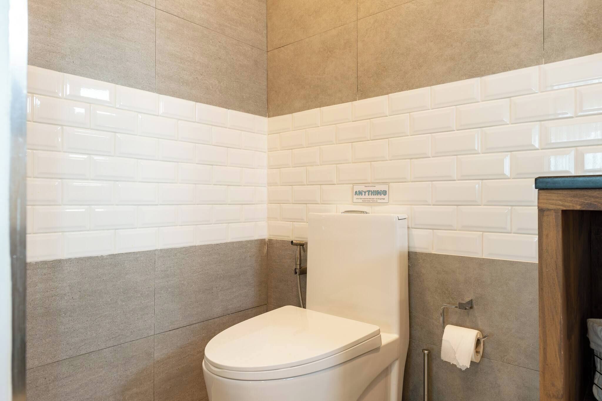 A bathroom with a toilet, a towel rack, and a sign that reads 'ANYTHING.'