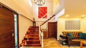 A staircase leading to a second floor, a wooden door, a sofa, and a patterned wall. - Luxurious retreat with premium amenities & comfort (Bangkok)
