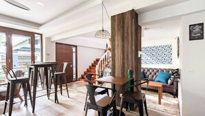 A modern living area with a dining table, chairs, a sofa, a staircase, and a view through a glass door. - Take Time Out on the Serene Balcony in the City (Bangkok)