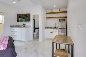 A compact living space with a kitchenette, a bed with a floral bedspread, and a small wooden table. - Groups Welcome! SPI Studio on Multi-Unit Property (South Padre Island)