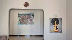 A hallway with three framed artworks on the walls, a patterned rug on the floor, and a decorative wall piece above the artwork.