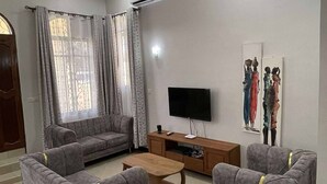 A living room with a sofa set, a coffee table, a TV, and artwork on the wall.